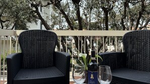 An outdoor seating area with wicker chairs and a table set with wine glasses and a bottle. - Hotel Atlantico (Rosignano Marittimo)
