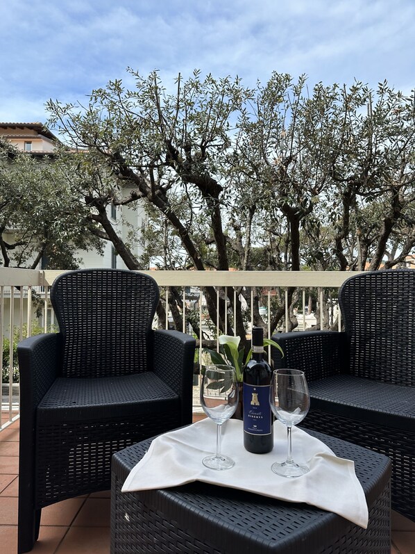 Un espacio al aire libre con sillas de mimbre y una mesa con copas de vino y una botella.