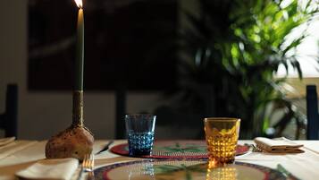 Una vela sobre una mesa con dos vasos y un plato.