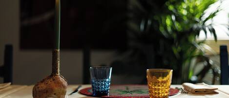 A candle on a table with two glasses and a plate.