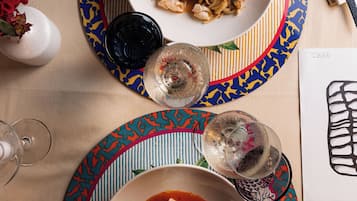 A dining table with two plates of seafood pasta and a glass of wine.