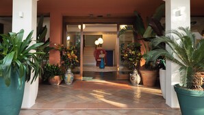 A hotel entrance with a tiled floor, large potted plants, and a staircase leading to the interior. - Hotel Atlantico (Rosignano Marittimo)