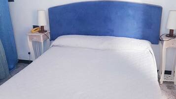 Ein Hotelzimmer mit einem Bett, zwei Nachttischen, einem gerahmten Bild an der Wand und einem blauen Kopfteil.