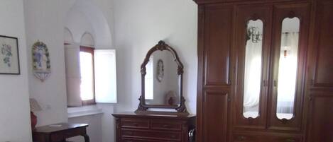 A bedroom with a large bed, a wooden dresser, a mirror, and a chandelier.