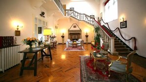 Uma sala de estar ampla com piso de madeira, lareira e escada com corrimão vermelho.