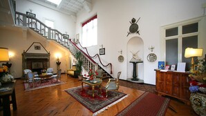 Uma sala de estar espaçosa com uma escadaria imponente, lareira e diversos arranjos de assentos.