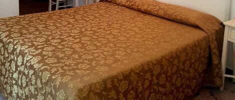 Un dormitorio con una cama grande, un escritorio, una silla y una araña.