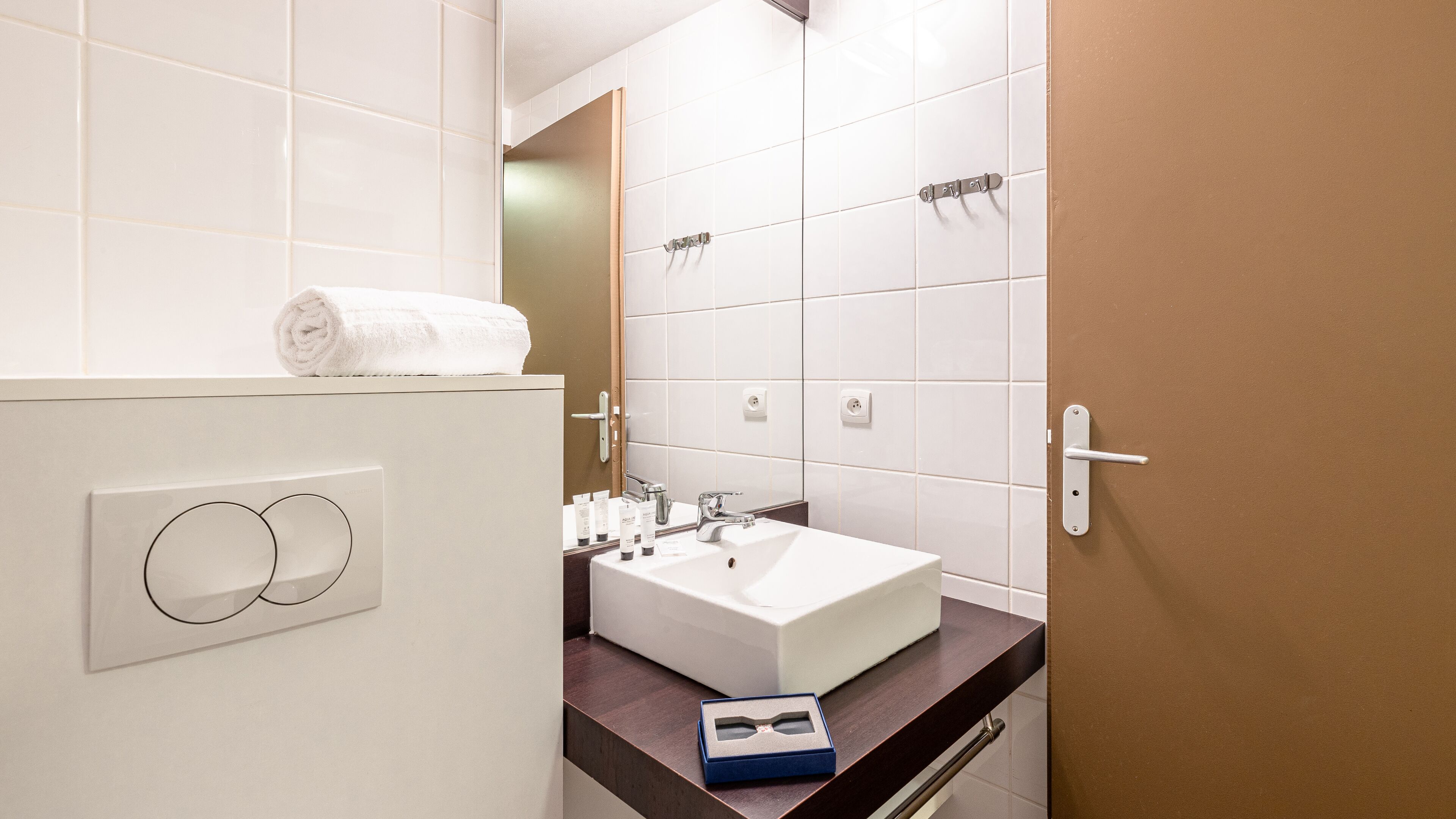 A modern bathroom with a white sink, a towel on the counter, and a mirror.
