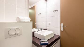 A modern bathroom with a white sink, a towel on the counter, and a mirror.