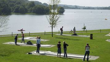 A park with a lake, people engaging in activities, and a boat in the water.