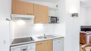 Una cucina moderna con mobili bianchi, un forno a microonde integrato, un fornello e una lavastoviglie.