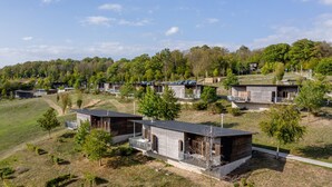 A modern resort with multiple wooden cabins, each featuring a balcony and a view of the surrounding greenery.