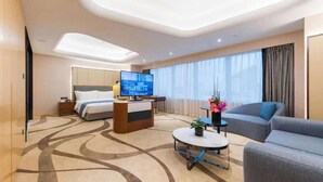 A modern hotel room with a bed, a desk with a computer, a sofa, and a small table with a plant. - Howard Johnson Wyndham Leonora plzaz Shanghai (Shanghai)