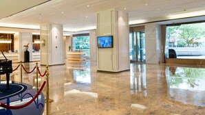 A spacious lobby with a grand piano, a television screen, and a red rope barrier. - Howard Johnson Wyndham Leonora plzaz Shanghai (Shanghai)