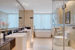 Un baño moderno con una bañera grande, un inodoro separado y un lavamanos.