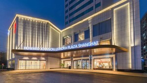The exterior of Howard Johnson Leonora Plaza Shanghai with a modern design, featuring a prominent entrance and illuminated signage. - Howard Johnson Wyndham Leonora plzaz Shanghai (Shanghai)