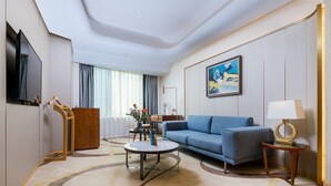 A modern hotel room with a sofa, coffee table, and a TV mounted on the wall. - Howard Johnson Wyndham Leonora plzaz Shanghai (Shanghai)