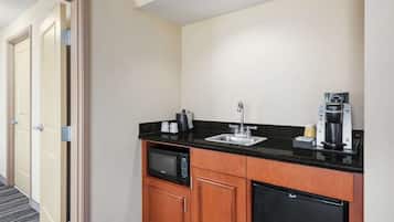 Cocina de hotel compacta con microondas, cafetera, lavaplatos y refrigerador.