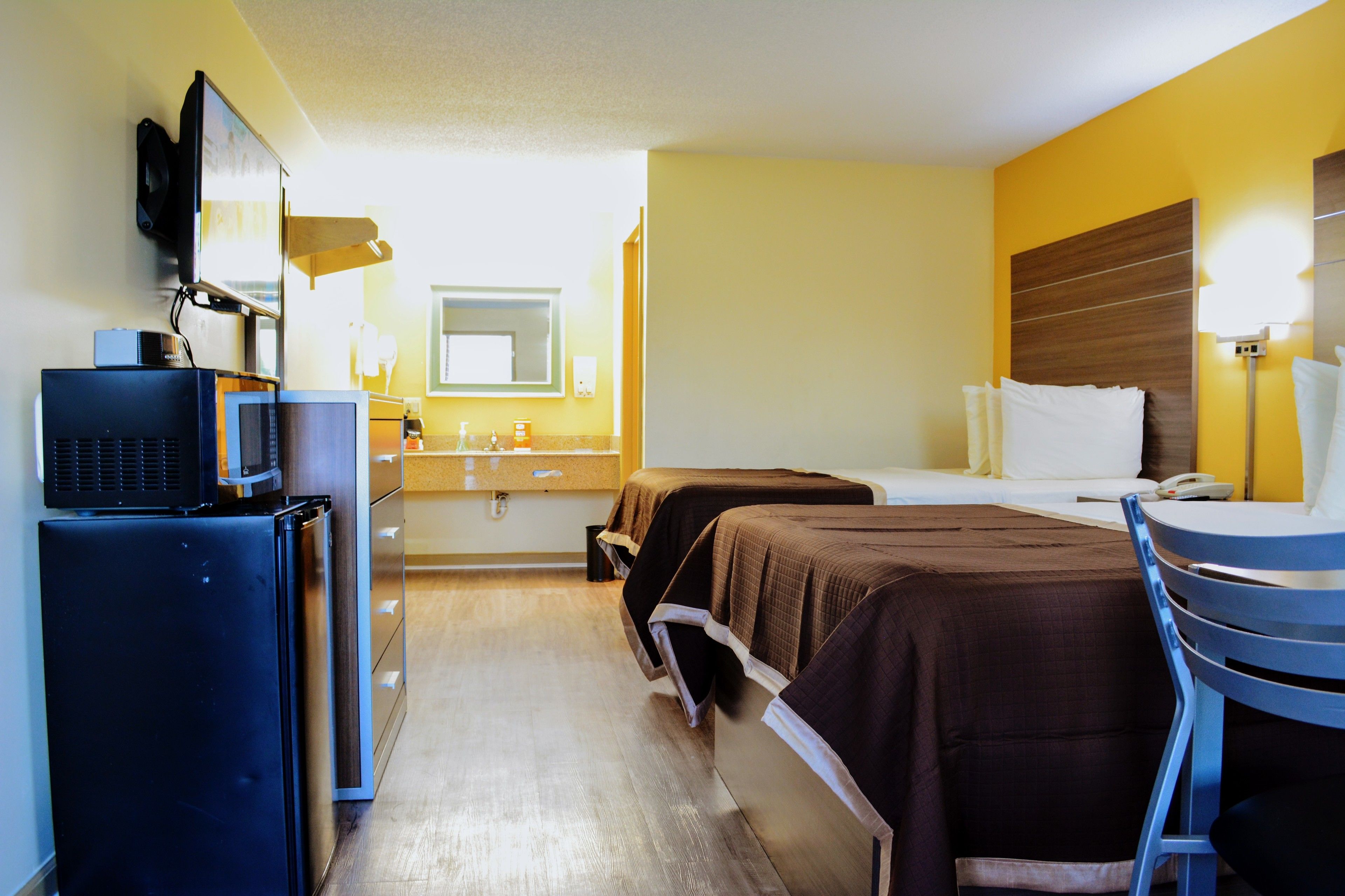 Una habitación de hotel con cama, escritorio, silla, televisor y un minibar.