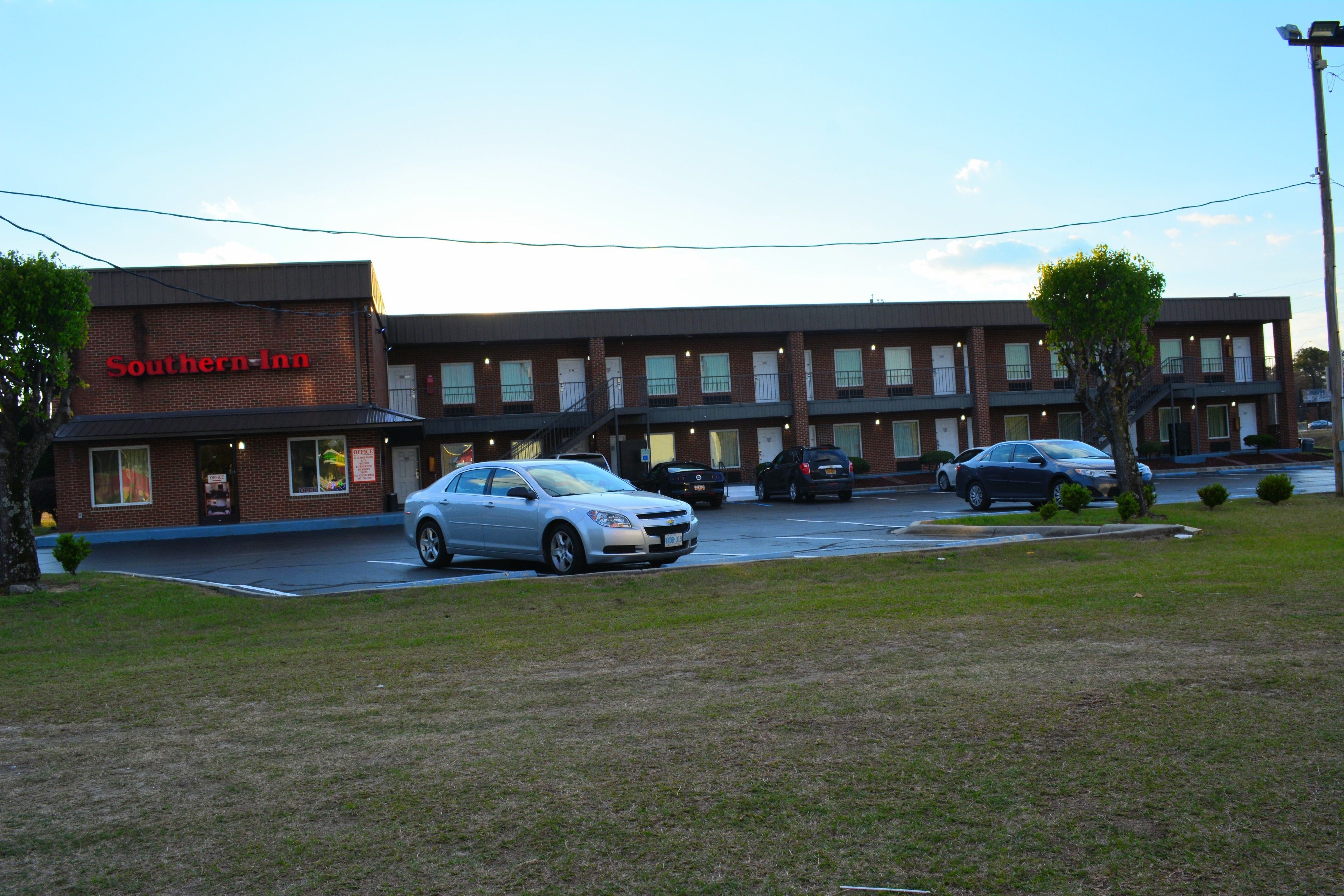 Een Southern-Inn gebouw met een parkeerplaats en geparkeerde auto's ervoor.