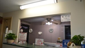 A hotel reception area with a reception desk, a ceiling fan, a sign indicating a sanitation rating of A 97.0, and a plant on the counter. - Southern Inn Lumberton (Lumberton)