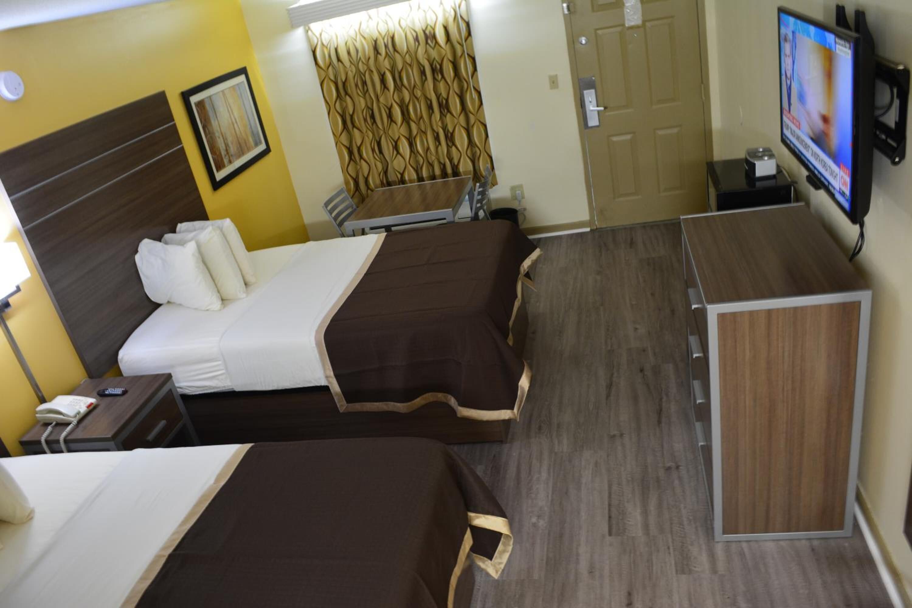A hotel room with two beds, a TV, a desk, and a wardrobe.