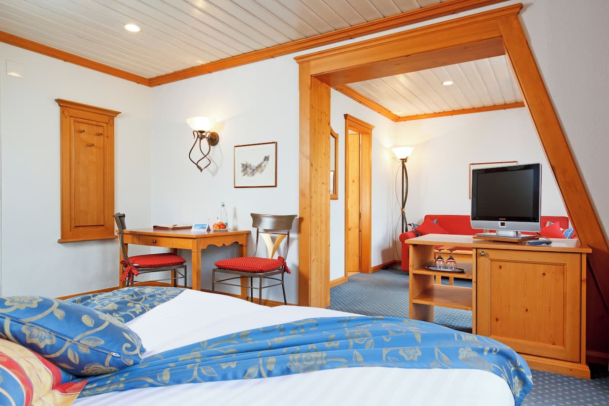 Ein Schlafzimmer mit Bett, Schreibtisch, Stuhl, Fernseher und einem kleinen Tisch.