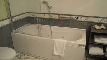 A bathroom with a bathtub, a toilet, and a shelf with towels.