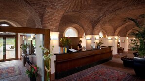 A reception area with a wooden reception desk, arched brick ceiling, and a large window. - Albergo dell'Agenzia (Bra)