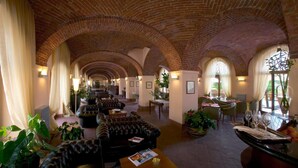 A spacious lobby with leather sofas, a bar area with glasses, and a brick ceiling. - Albergo dell'Agenzia (Bra)