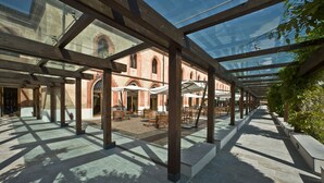An indoor courtyard with a glass roof, stone flooring, and wooden furniture. - Albergo dell'Agenzia (Bra)