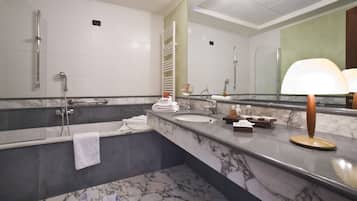 A modern bathroom with a large mirror, a bathtub, a shower, and a marble countertop.