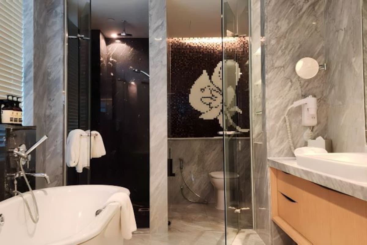 Een moderne badkamer met een vrijstaand bad, een douche met glazen wanden en een marmeren wand met een bloemenreliëf.