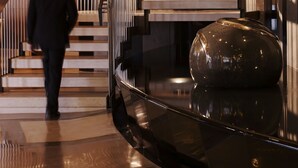 A modern staircase with a sleek design, a polished floor, and a reflective spherical object at the bottom.