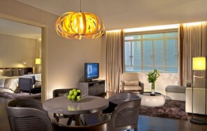 A hotel room with a dining area, a television, a plant, and a large window with curtains. - Ascott Raffles Place Singapore (Singapore)