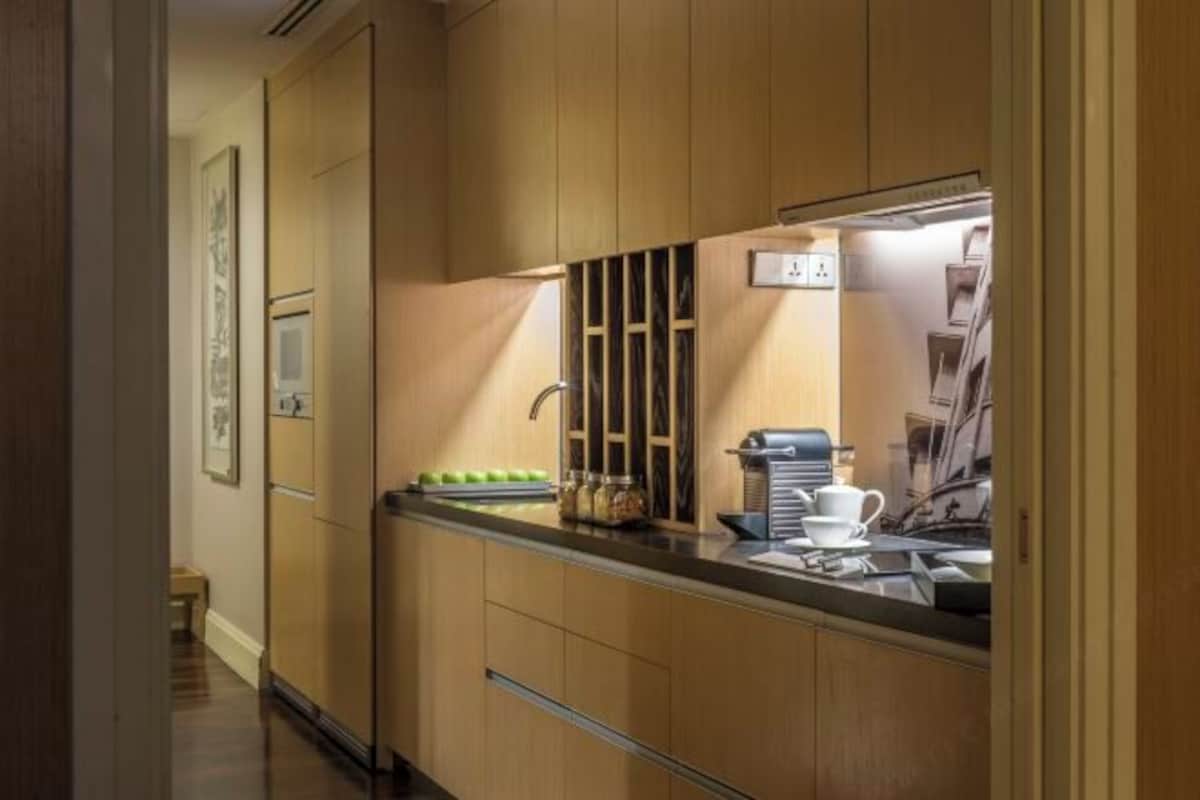 Een moderne keuken met houten kastjes, een inbouwoven en een koffieapparaat.