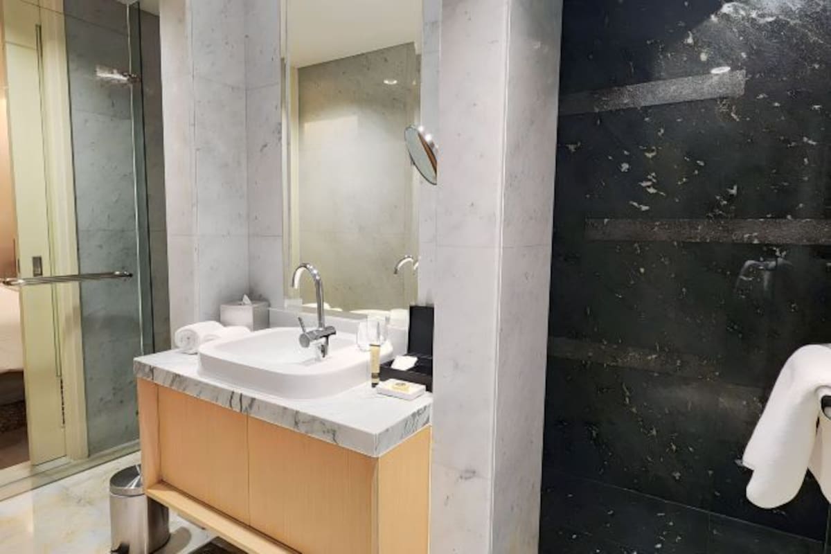 Een moderne badkamer met een marmeren wastafel, een douchecabine met glazen wanden en een wand betegeld met zwart tegelwerk.