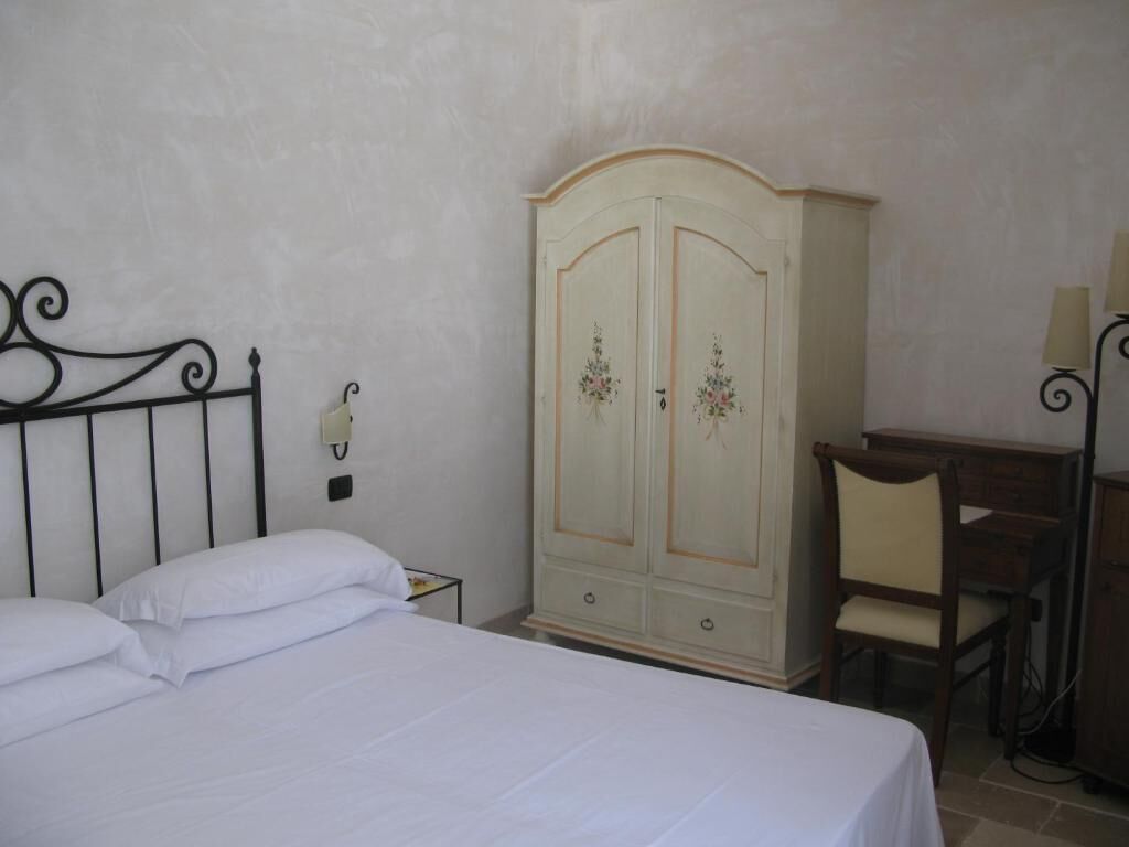 A bedroom with a bed, a wardrobe, a desk, and a chair.