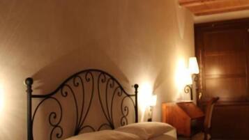 Una camera da letto con soffitto in legno, struttura del letto in metallo, comodino con lampada e una sedia.