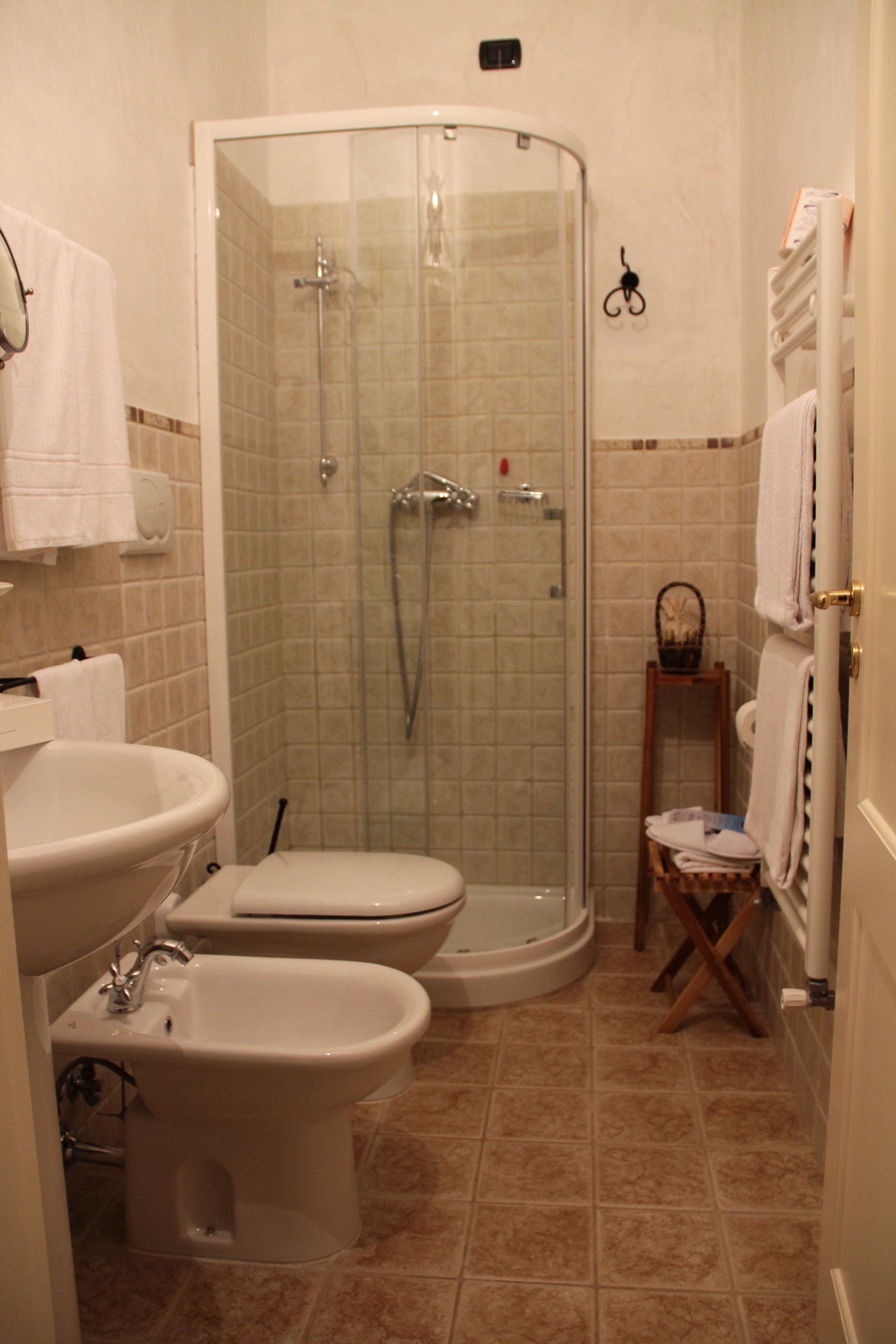 Un baño con ducha compartimentada con vidrio, un bidé, un inodoro y un lavamanos.