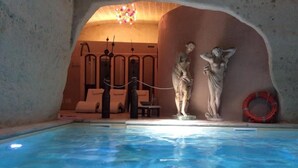 An indoor swimming pool with a stone wall, a lifebuoy, and a statue. - Masseria Fortificata Donnaloia  (Monopoli)