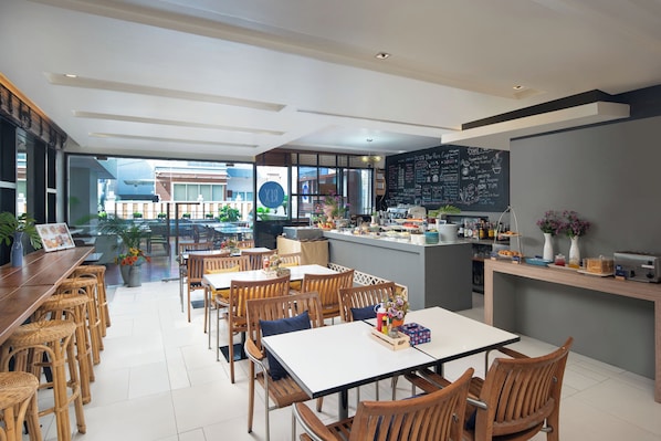 Um café moderno com área de bar, mesas e cardápio em lousa.