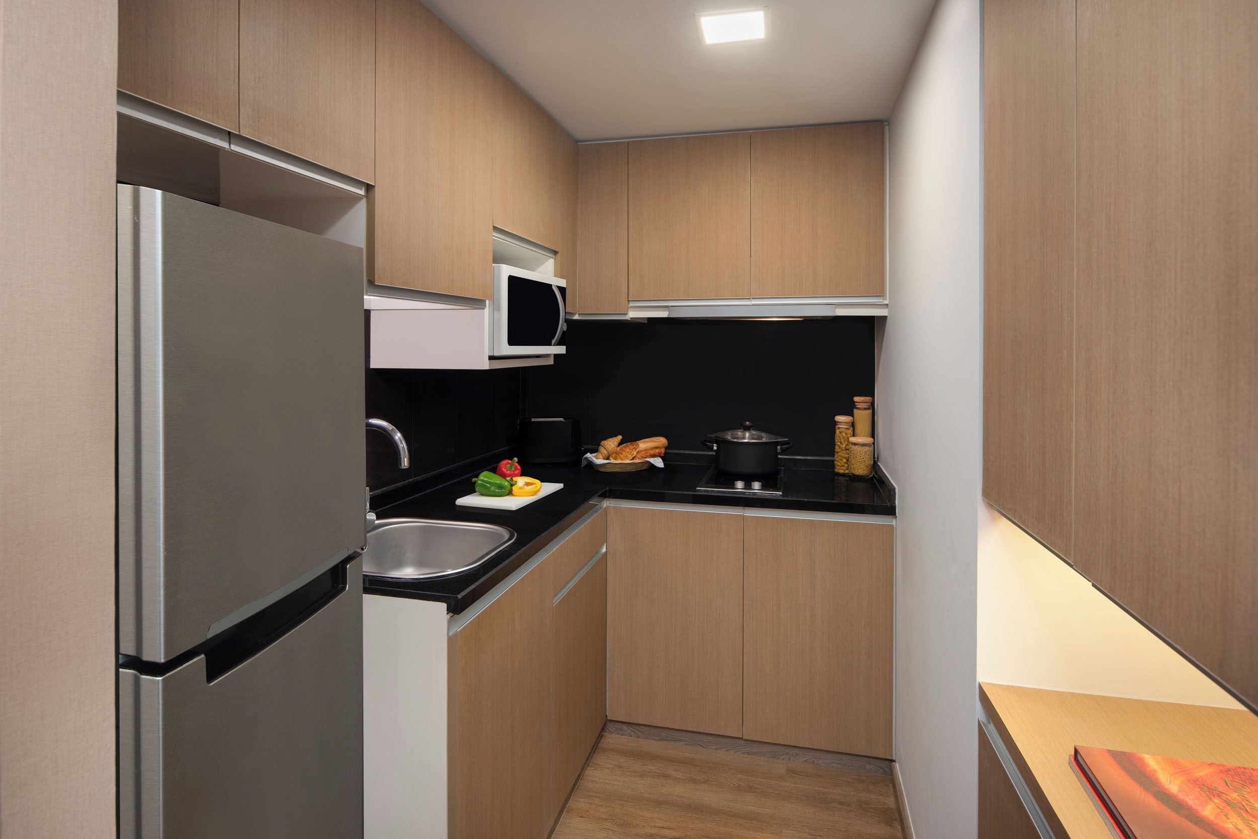 Eine kleine Küche mit Kühlschrank, Mikrowelle, Spüle und Holzschränken.