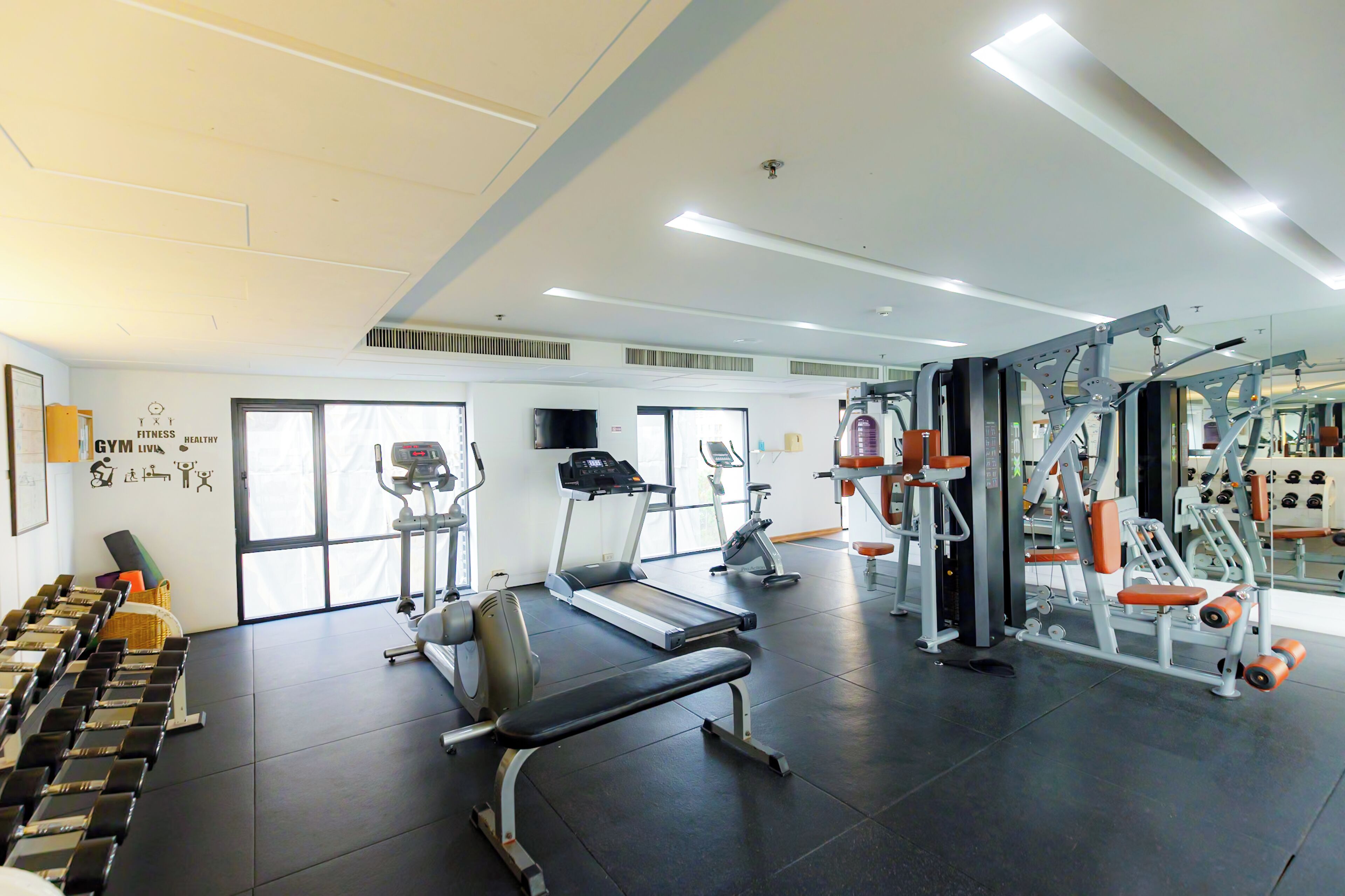 A gym with treadmills, weight machines, and dumbbells.