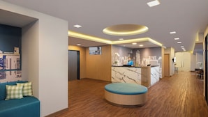 A hotel lobby with a reception desk, seating area, and a cityscape mural.