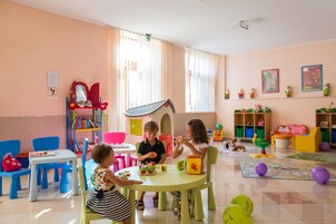 Une salle de jeux pour enfants aux couleurs vives, avec une table, des chaises et divers jouets.