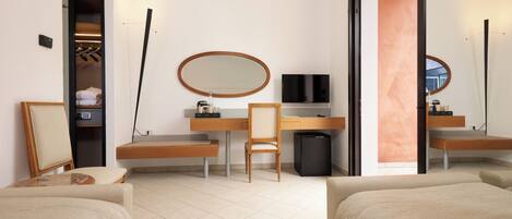 A hotel room with a bed, a desk with a chair, a TV, a mirror, and a wardrobe.