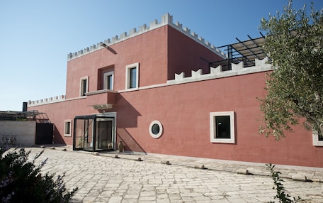 Un edificio con fachada roja, entrada de vidrio y patio empedrado con piedra.