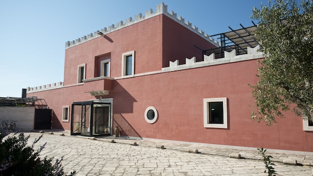 A building with a red facade, a glass entrance, and a stone-paved courtyard.