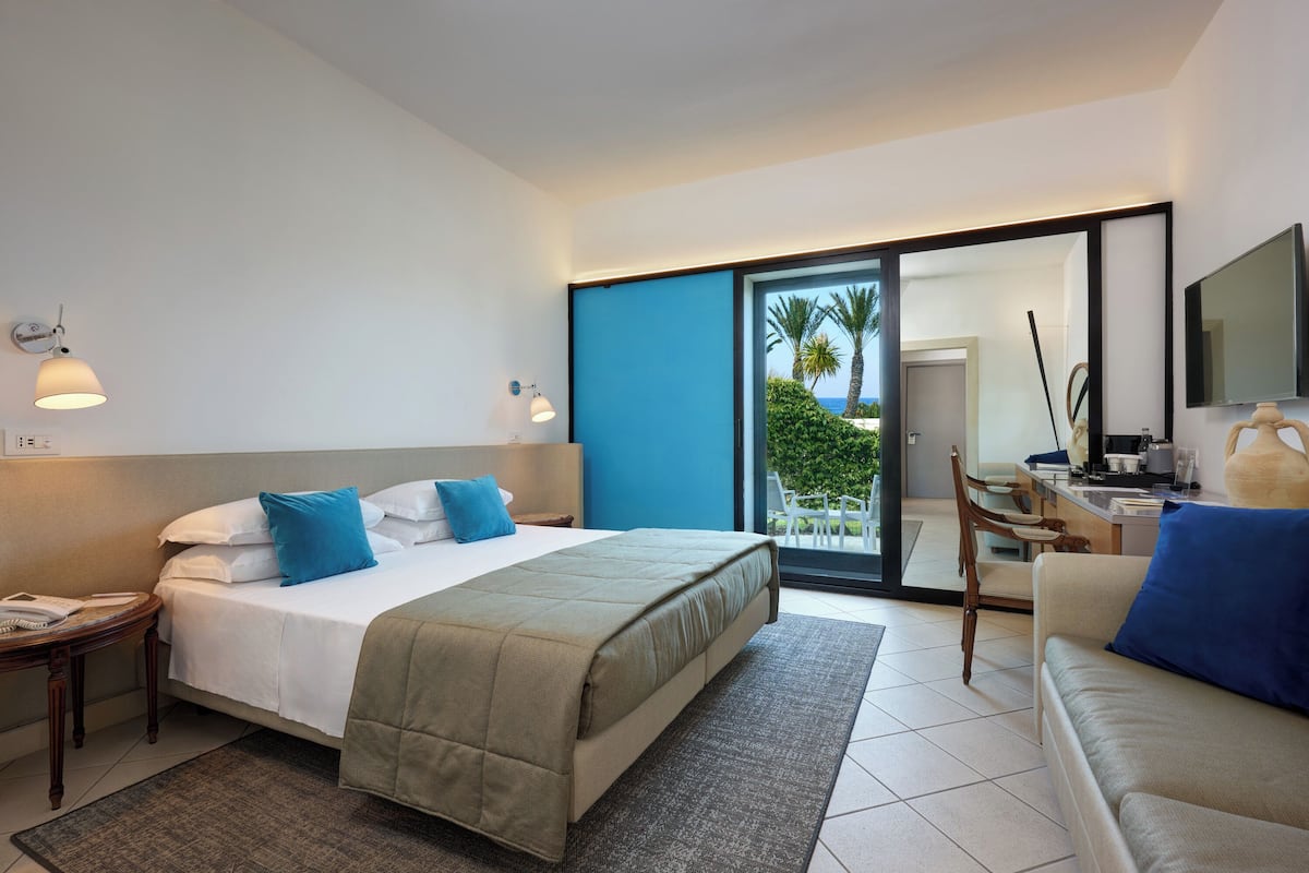 Een hotelkamer met een bed, een bank, een bureau en uitzicht op het omliggende landschap.